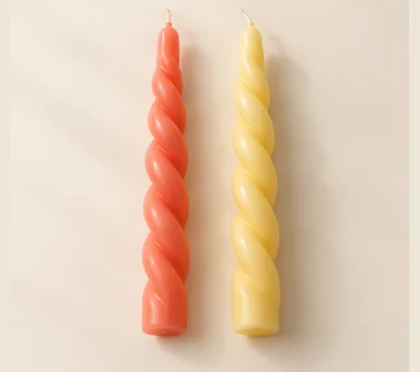 Two twisted taper candles in coral and butter yellow